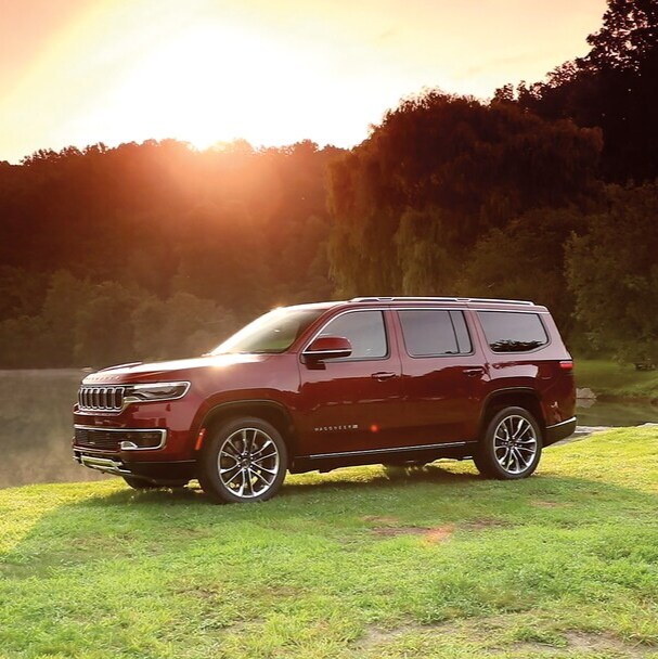 Jeep red Jeep Grand Wagoneer parked in a grassy field
