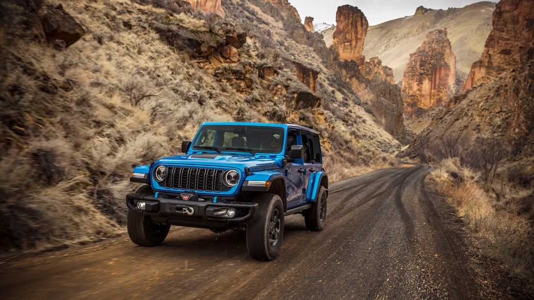 blue Jeep Wrangler 4xe driving in a desert valley