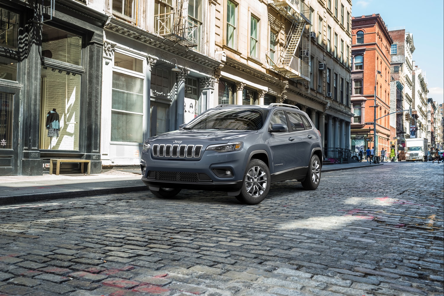 2022-Jeep-Cherokee-LatitudeLux-SUV-L01.png grey Jeep Cherokee parked on a cobblestone street