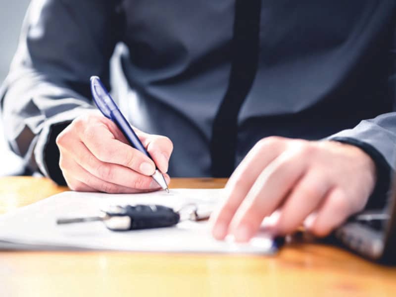 Let's Make Deal A person signing some paperwork with keys on the table.