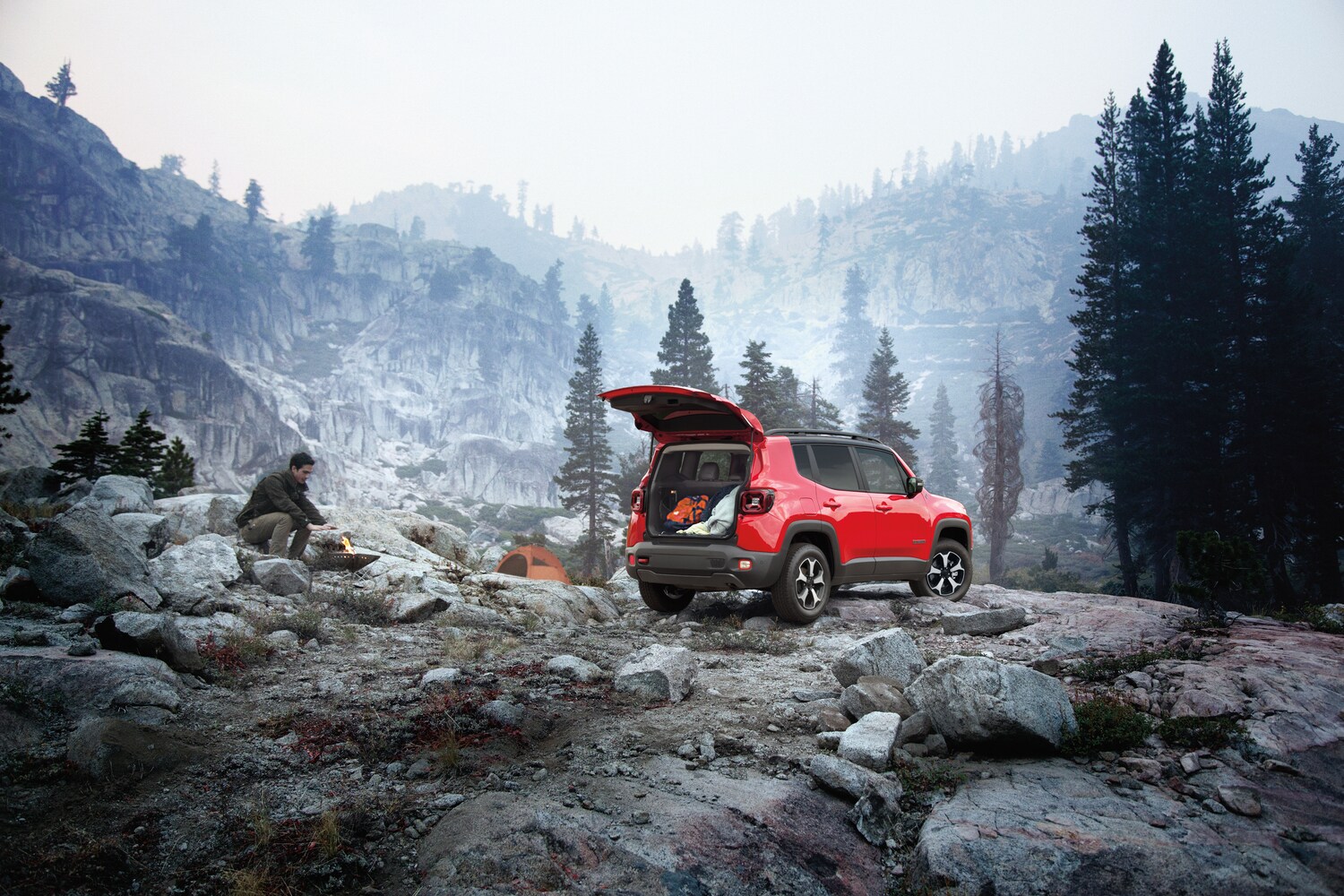 2021-Jeep-Renegade-Trailhawk-SUV-L04.png red Jeep Renegade parked on a rock outcropping with the trunk open