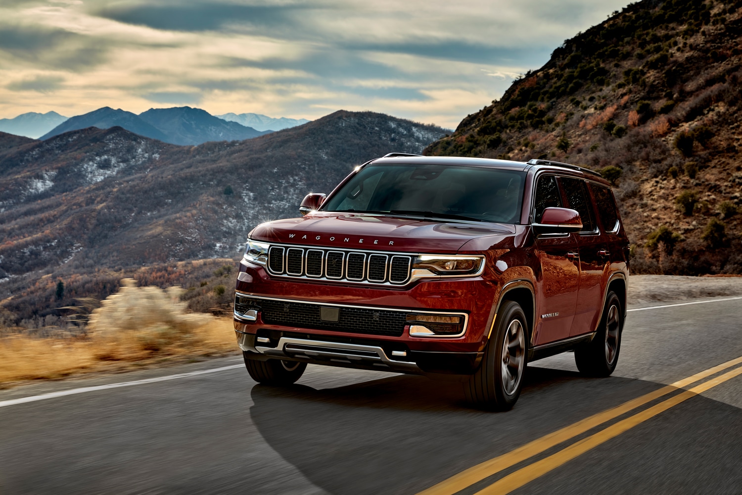 2022-Jeep-Wagoneer-SeriesII-SUV-L14.png red Jeep Wagoneer luxury SUV driving down a highway