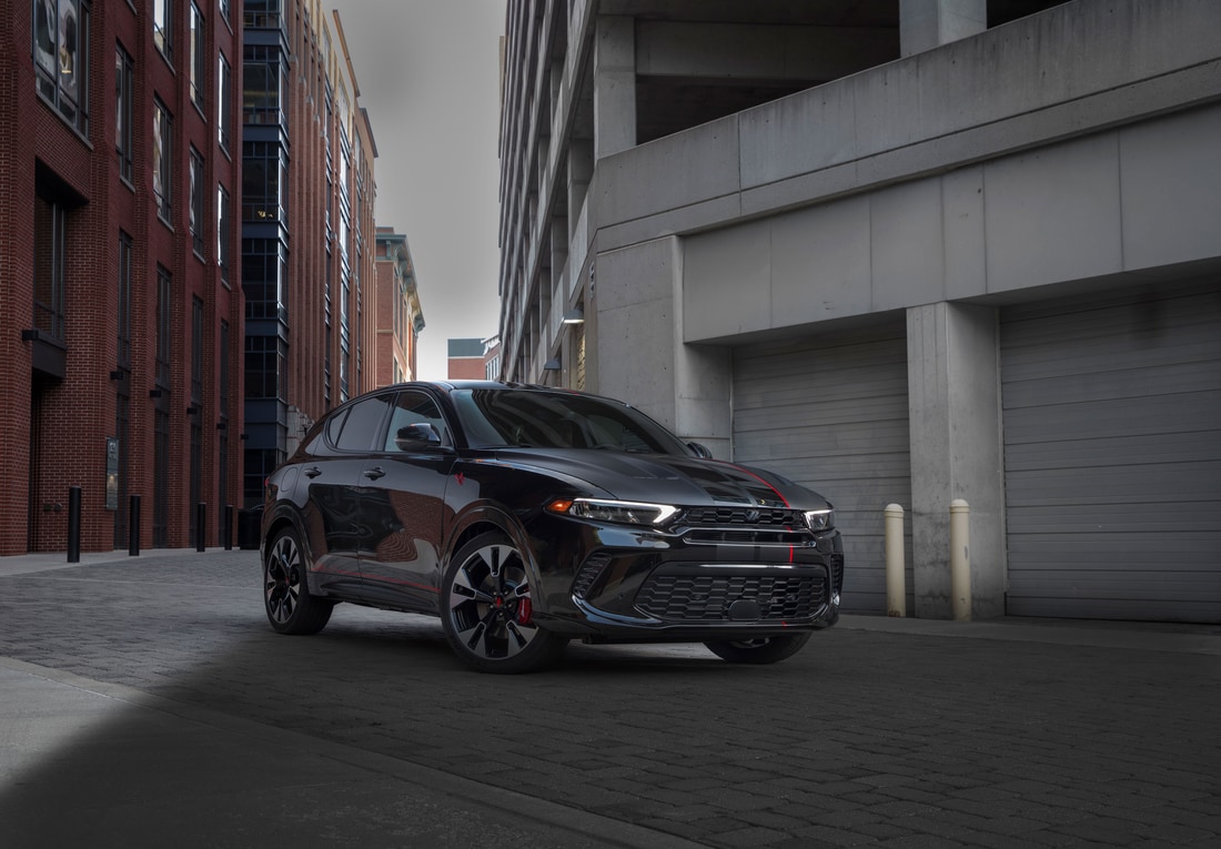 2024-Dodge-Hornet-SUV-L02.png dark grey Dodge Hornet SUV parked in front of an alley garage