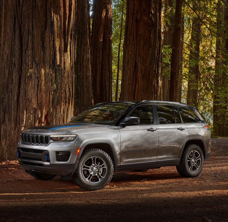 2024-Jeep-GrandCherokeeWL-4xe-Trailhawk-SUV-L17.png silver Jeep Grand Cherokee 4xe SUV parked in a wooded area