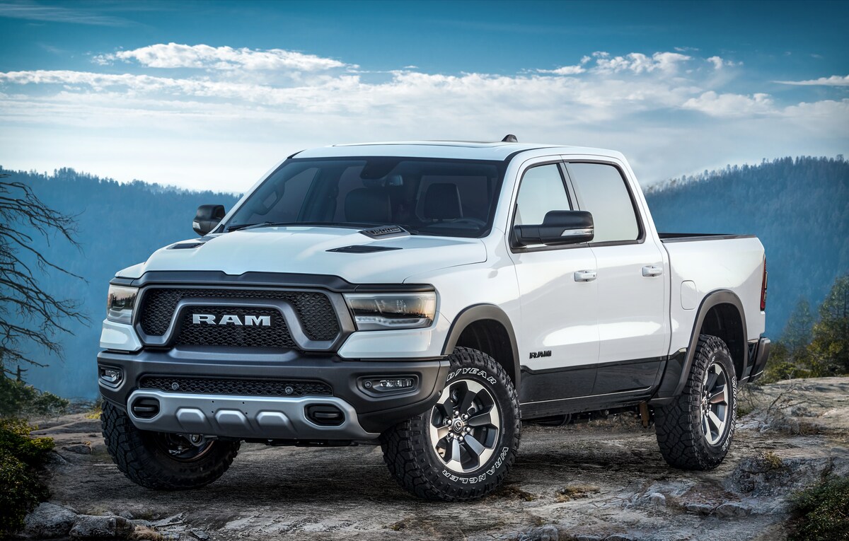 2022-RAM-1500-Rebel-CrewCab-Truck-L15.png white Ram 1500 Rebel truck parked on an outcropping with a mountain range in the back