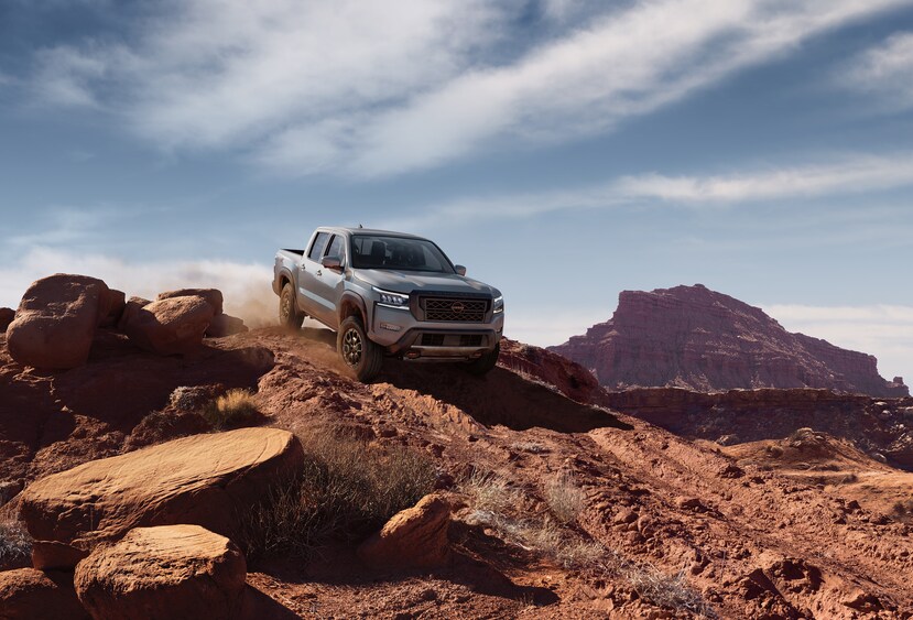 2022-Nissan-Frontier-PRO4X-CrewCab-Truck-L02.png silver Nissan Frontier truck bouldering down over red desert rocks