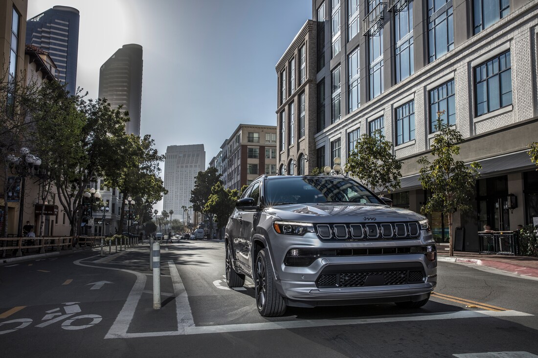 2022-Jeep-Compass-HighAltitude-SUV-L07.png dark gray Jeep Compass SUV parked at a city crossing