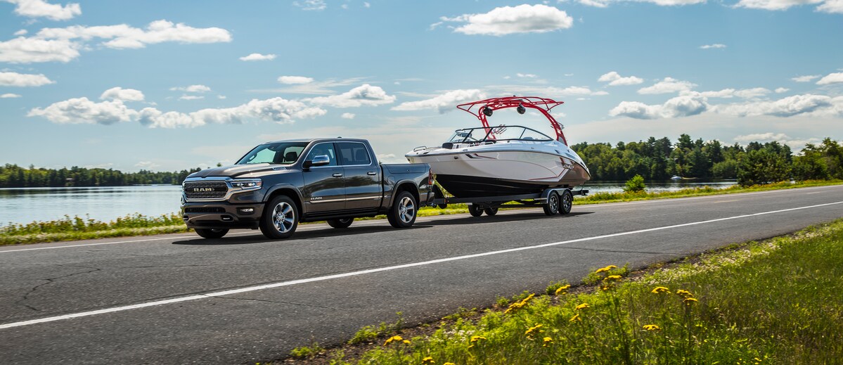 2022 Ram 1500 Limited Crew Cab Truck.png black Ram 1500 truck towing a boat near a lake