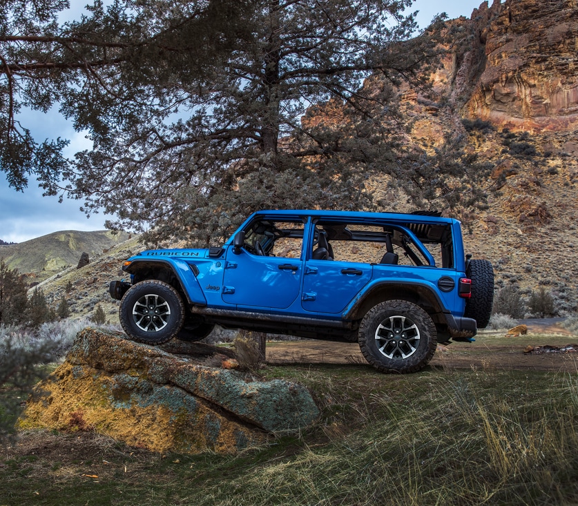 2024-Jeep-Wrangler-Rubicon4xe-4Door-SUV.png blue Jeep Wrangler SUV parked on a ridge