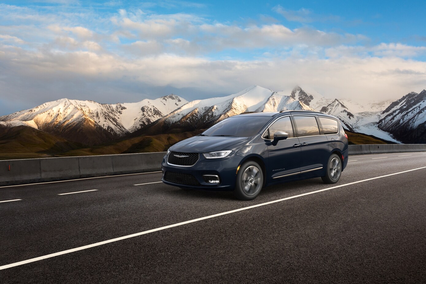 blue Chrysler Pacifica driving past snowy mountains