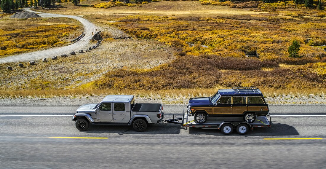 2023-Jeep-Gladiator-HighAltitude-Truck-L04.png silver Jeep Gladiator truck towing an old Jeep Wagoneer