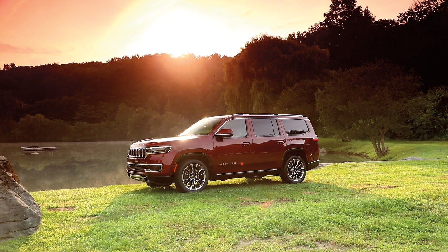 red Jeep Grand Wagoneer parked in a grassy field