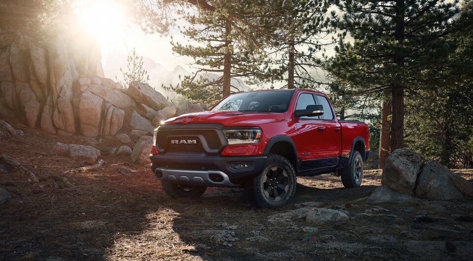 2019-RAM-1500-Rebel-CrewCab-Truck-L03.png red Ram 1500 truck parked in a forested area