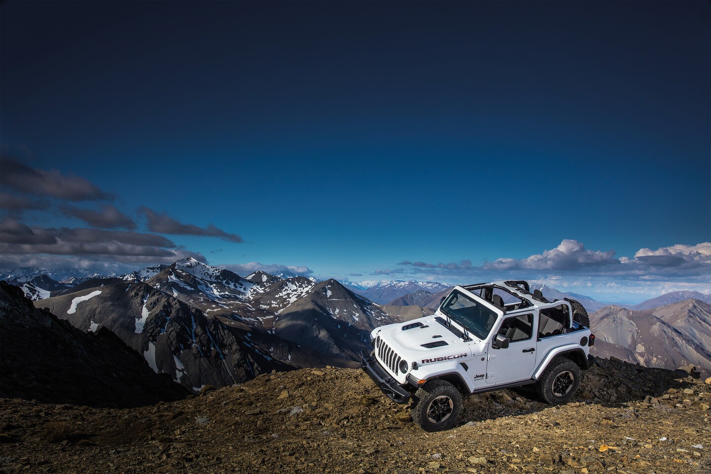 white Jeep Wrangler parked at an angle on a ridge