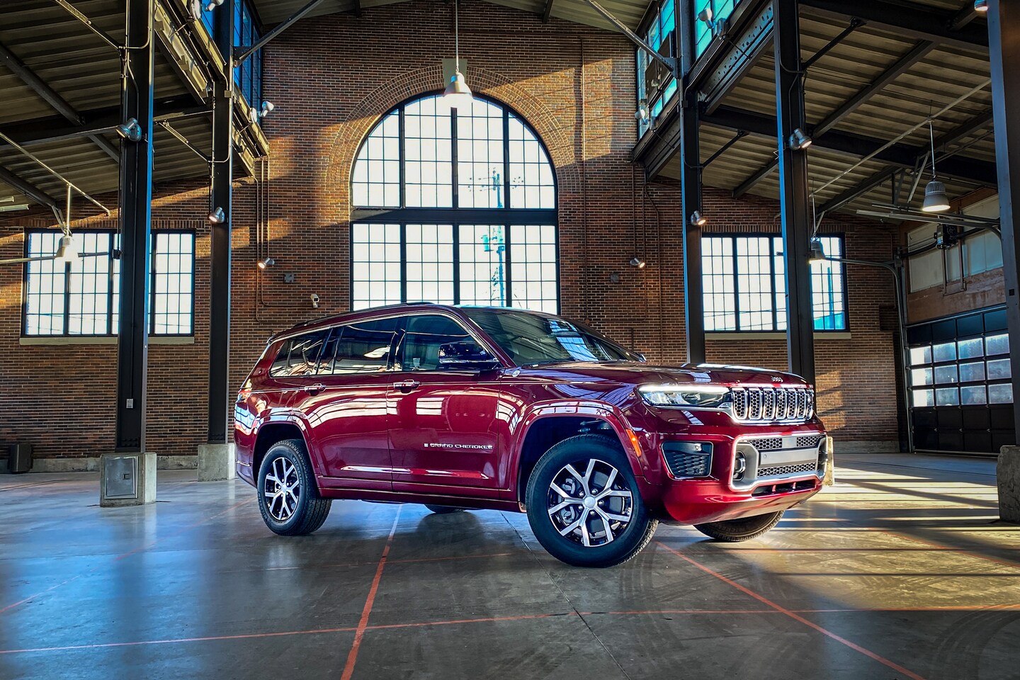 maroon Jeep Grand Cherokee SUV parked in a large brick manufacturing building