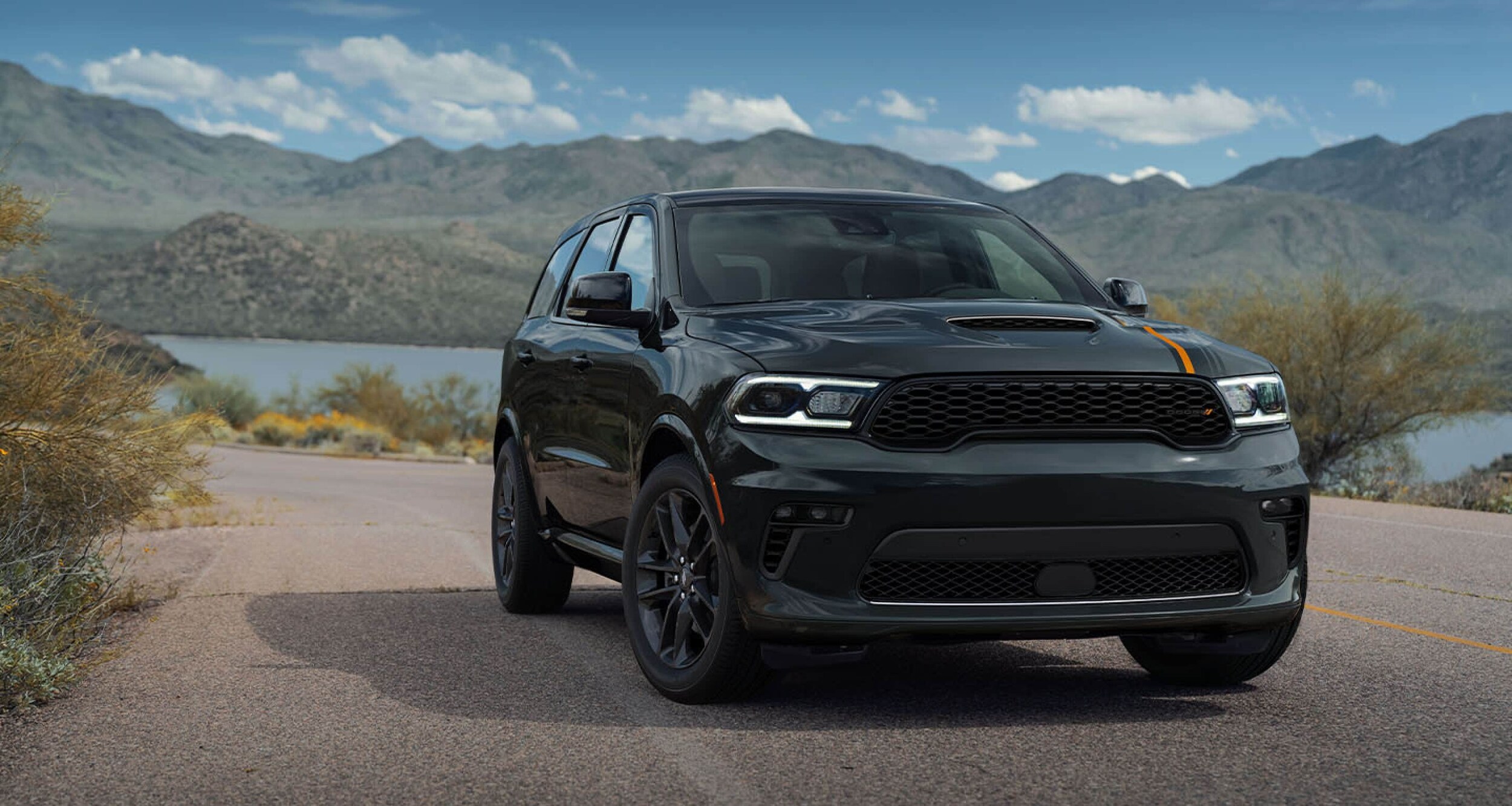 black Dodge Durango driving next to a mountain lake