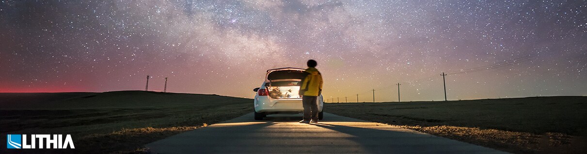 Build My Dream Car Rear view of one man glaring at the palette of milky way with car trunk open
