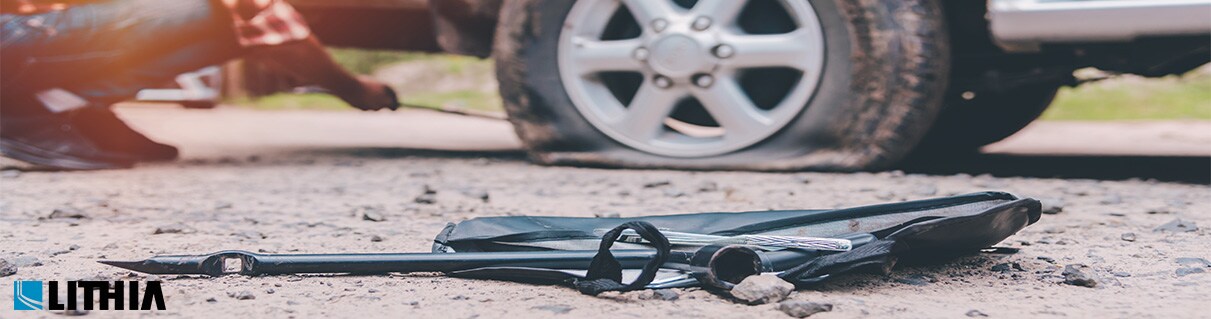 Top 10 Best Roadside Assistance Plans Man fixing a flat tire