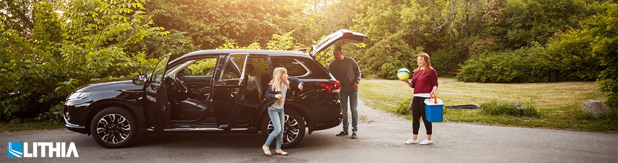 Tips for Family Car Shopping Family by black electric car against trees at park