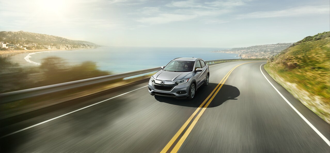 silver Honda car driving next to the coast