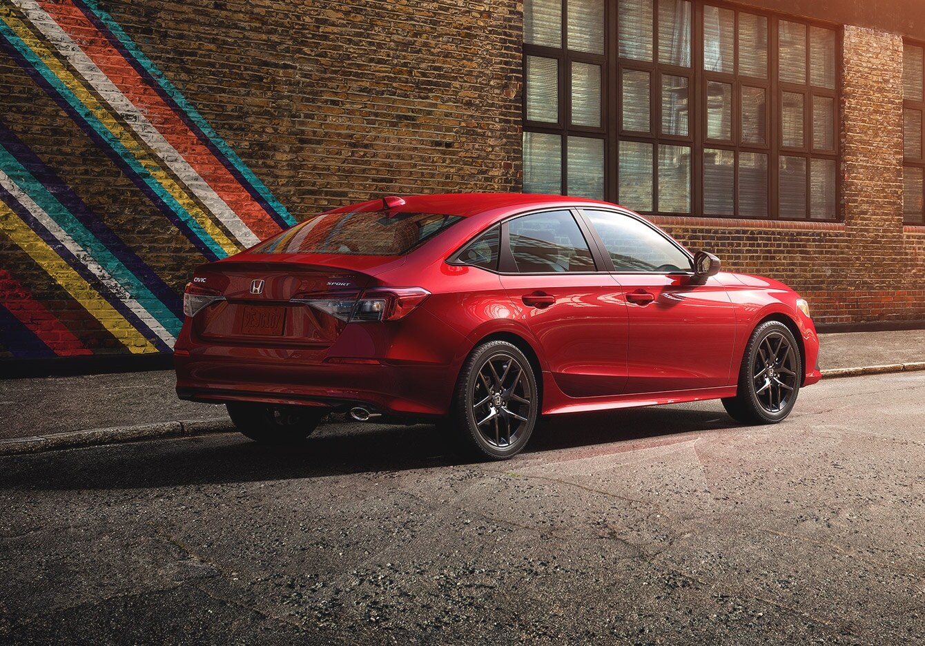red Honda Civic parked next to a painted brick wall
