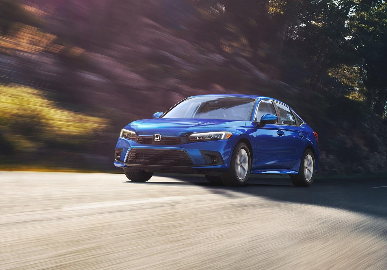 blue Honda Civic driving fast on a tree-lined road