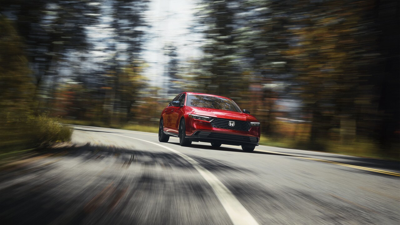 red Honda car driving in a wooded area