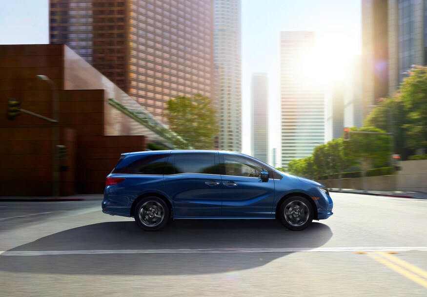 2022-Honda-Odyssey-Elite-Van-L09.png blue Honda Odyssey minivan driving through a downtown area