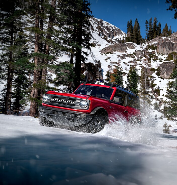 2023-Ford-Bronco-OuterBanks-2Door-SUV.png red Ford Bronco SUV driving through the snow