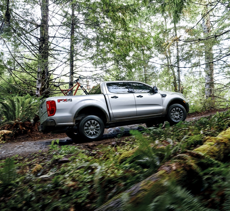 2022-Ford-Ranger-XLTSport-CrewCab-Truck.png white Ford Ranger truck driving up a forest trail