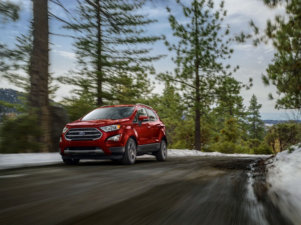 2021-Ford-EcoSport-Titanium-SUV-L04.png red Ford EcoSport SUV driving on a road lined with evergreen trees