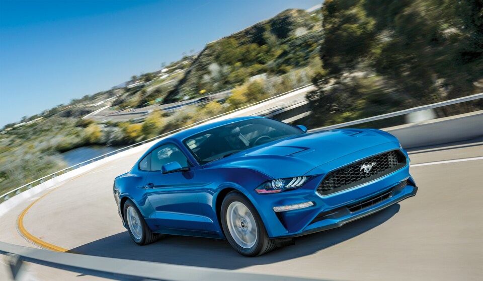 2020-Ford-Mustang-EcoBoost-Base-Coupe-L01.jpeg blue Ford Mustang speeding by on a freeway