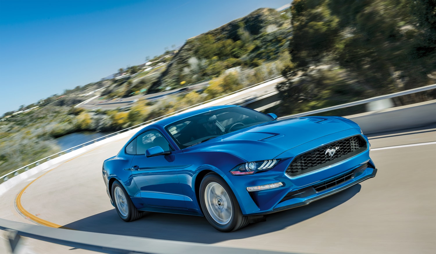 2020-Ford-Mustang-EcoBoost-Base-Coupe-L01.png blue Ford Mustang coupe driving around a curved hill-side road