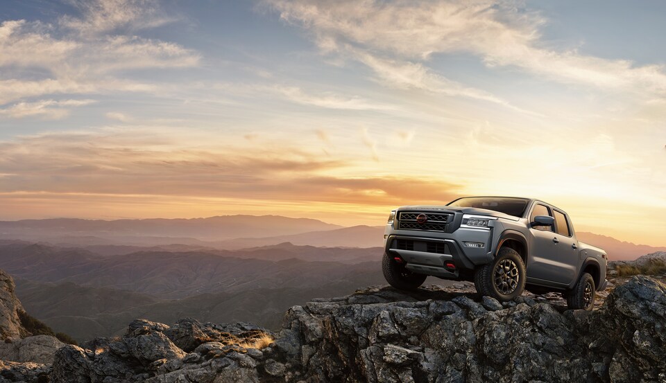 2022-Nissan-Frontier-PRO4X-CrewCab-Truck-L01.png silver Nissan Frontier truck parked on a rock outcropping