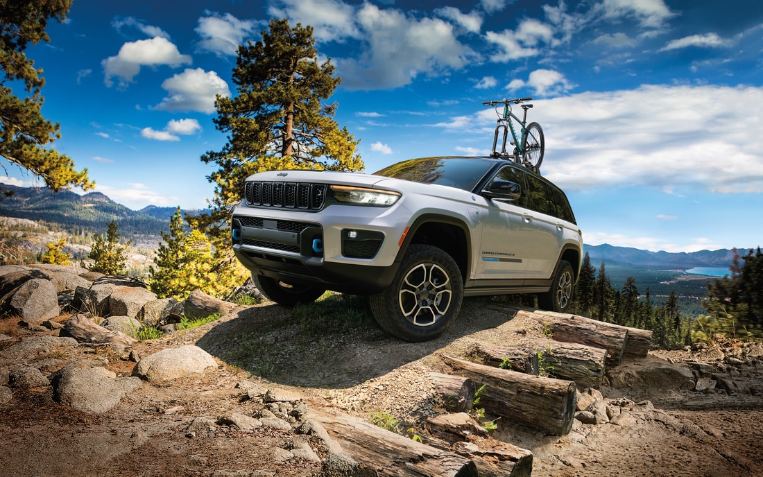 2022-Jeep-GrandCherokeeWL-4xe-Trailhawk-SUV-L10.png white Jeep Grand Cherokee 4xe hybrid SUV climbing over a steep ridge