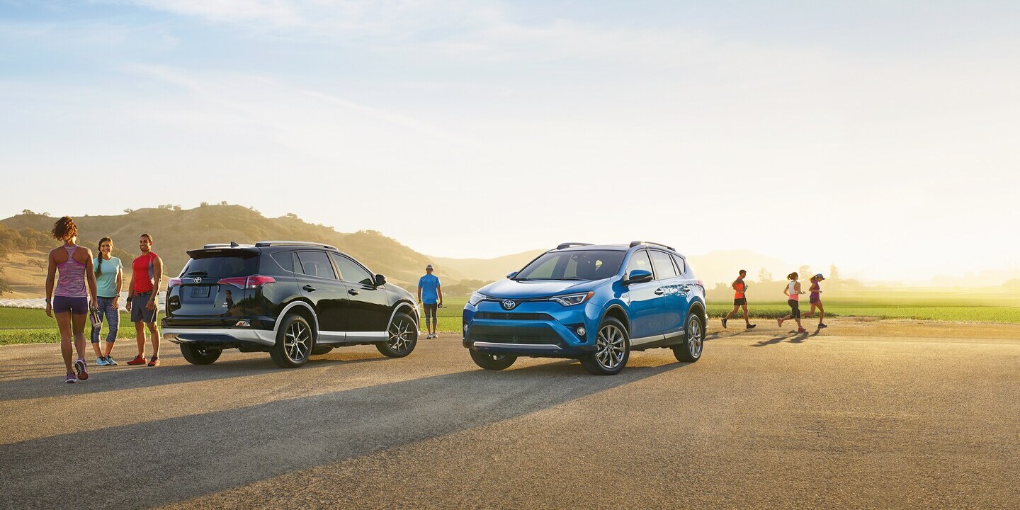black and blue Toyota SUVs parked in a gravel lot with joggers nearby