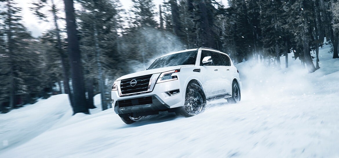 white Nissan SUV driving through the snow