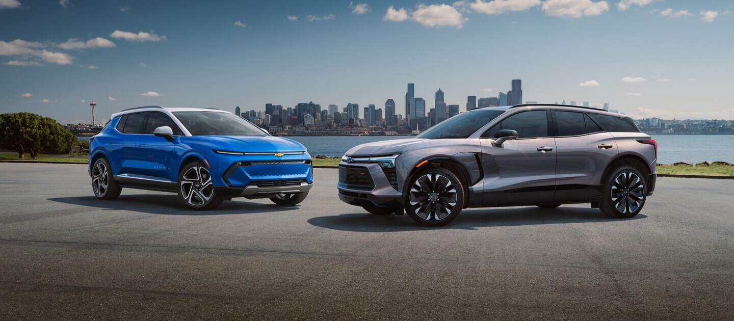 blue and grey Chevrolet SUVs in a parking lot with a city in the background