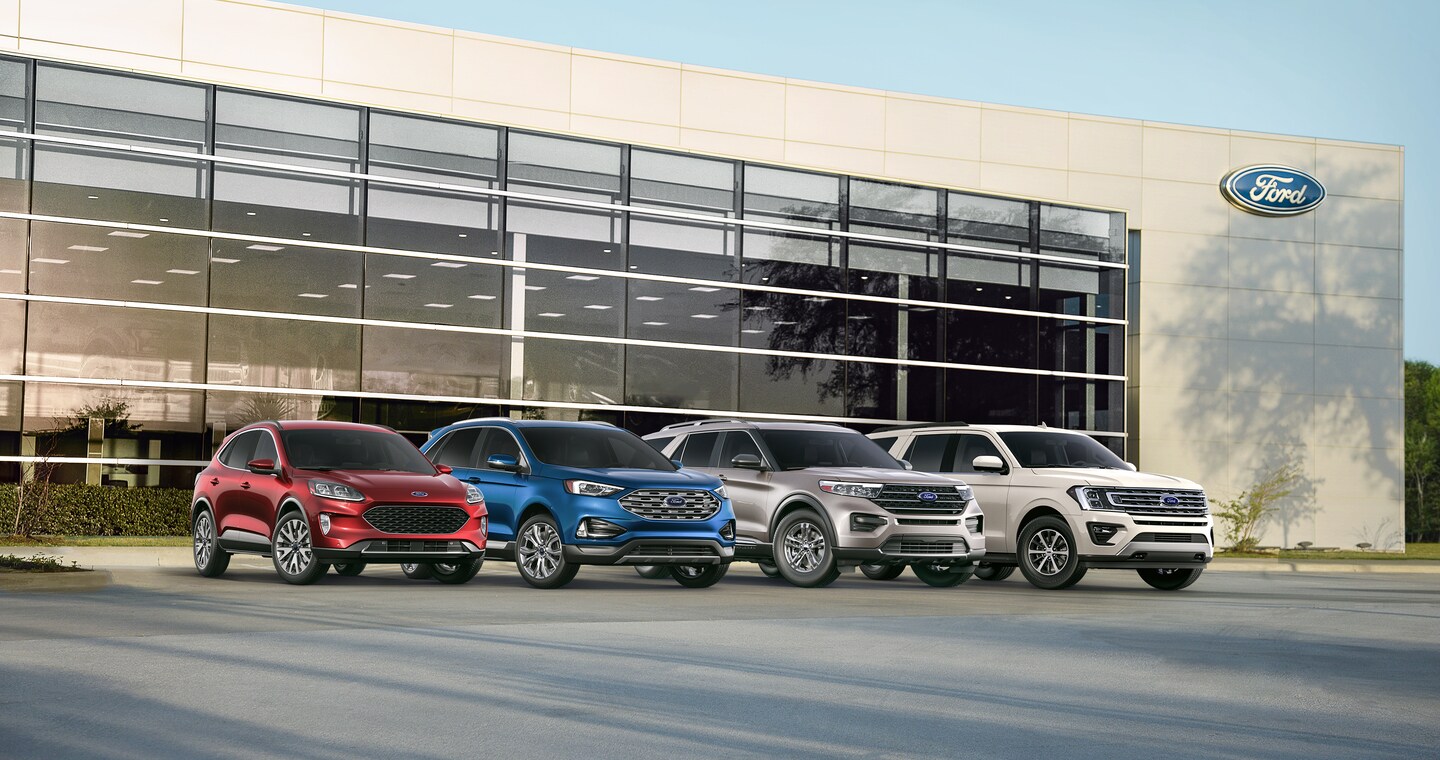 red, blue, grey and white Ford SUVs parked in front of a Ford dealership