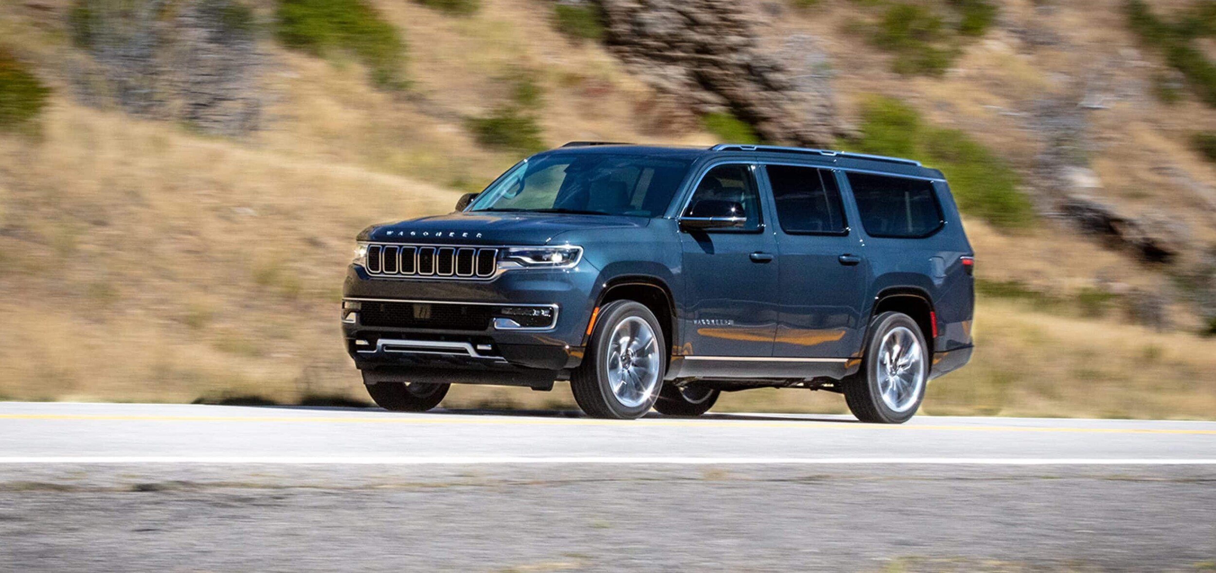 dark blue Jeep Wagoneer driving on a highway