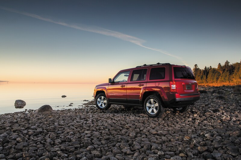 2014-Jeep-Patriot-Latitude-01.png red orange Jeep Patriot SUV parked on a pebble beach