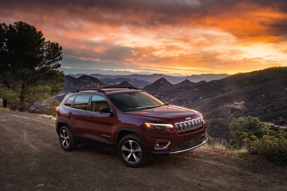 2022-Jeep-Cherokee-Limited-SUV-L03.png dark red Jeep Cherokee SUV parked on a dirt road, overlooking a valley at sunset