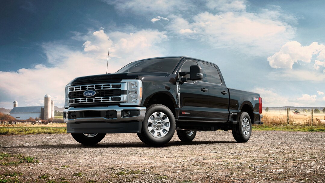 black Ford Super Duty diesel truck parked next to a farm