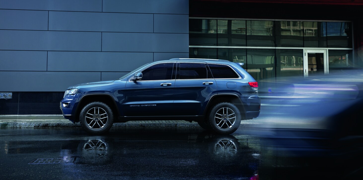 2021-Jeep-GrandCherokee-Limited-SUV-L05 (2).png blue Jeep Grand Cherokee SUV parked on a wet, city road