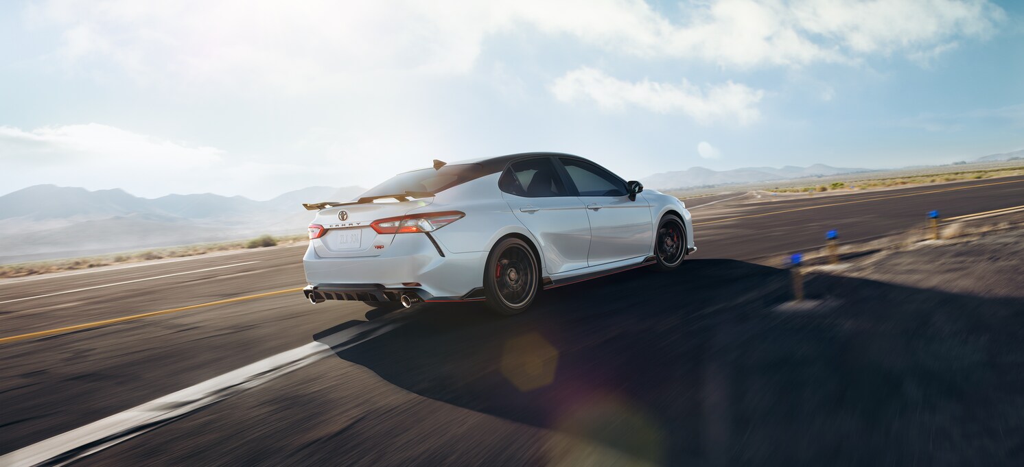 2020-Toyota-Camry-TRD-Sedan-L04.png white Toyota Camry sedan driving past a sunlit blurred background