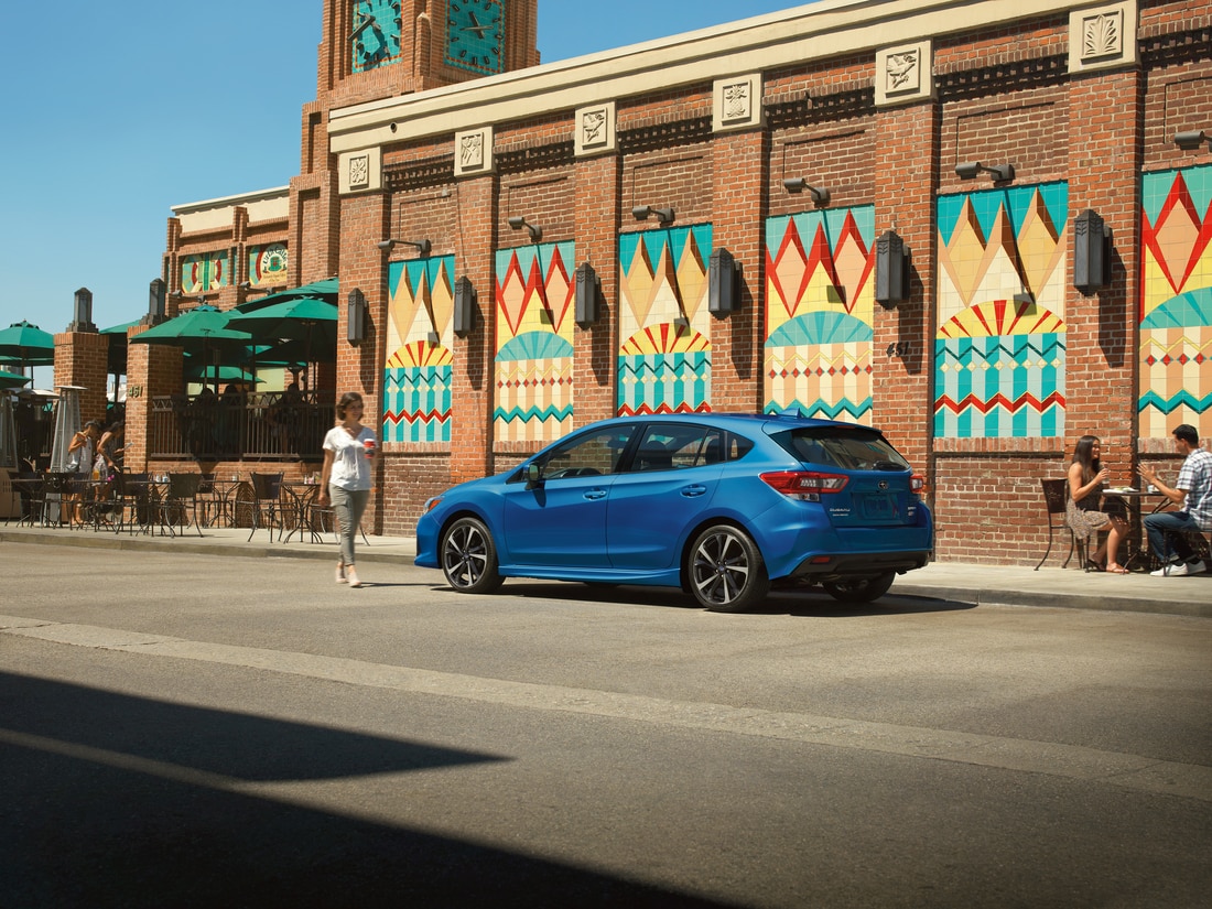 2022-Subaru-Impreza-Sport-Hatchback-L09.png blue Subaru Impreza sport sedan parked in front of a coffee shop with the driver walking towards it
