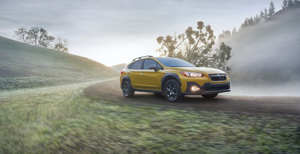 2023-Subaru-Crosstrek-Sport-Hatchback_1.png yellow Subaru Crosstrek driving on a dirt road in the fog