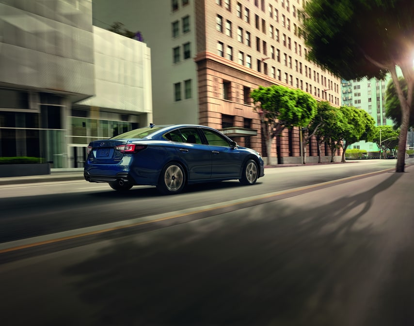 2021-Subaru-Legacy-TouringXT-Sedan-L05.png blue Subaru Legacy sedan driving through a tree-lined downtown area