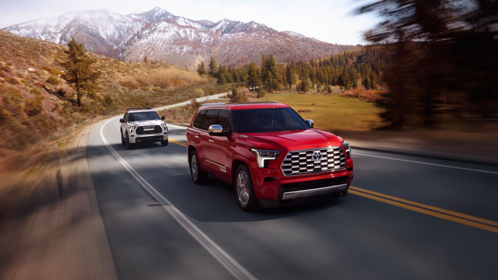 red Toyota Sequoia driving in front of a white Toyota Sequoia