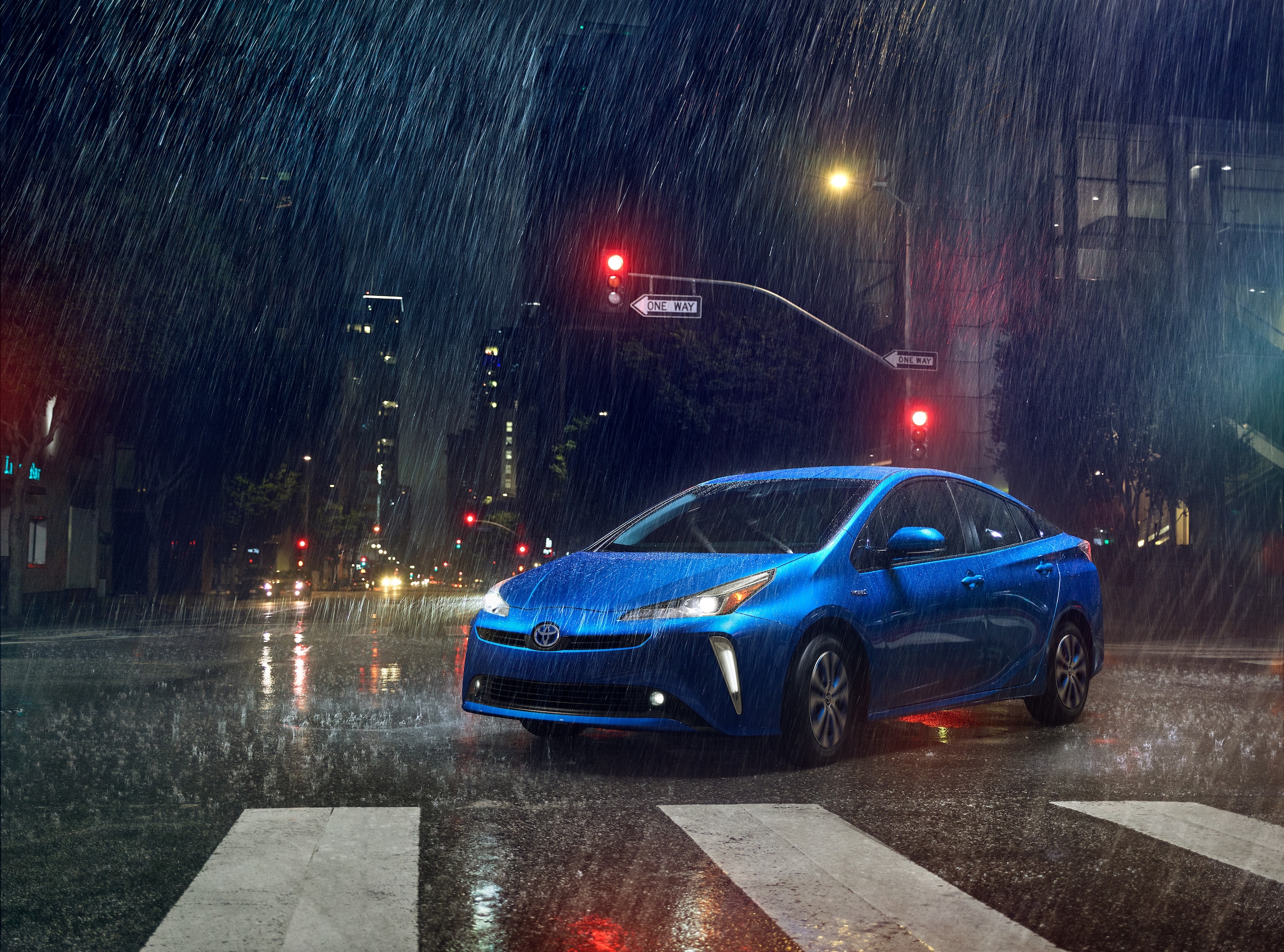 blue Toyota Prius driving on a city street on a rainy day